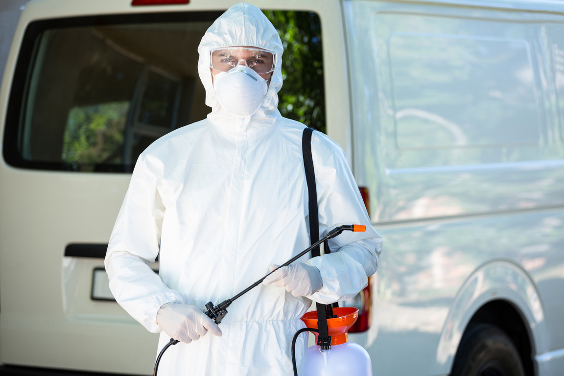 Pest control man standing behind a van